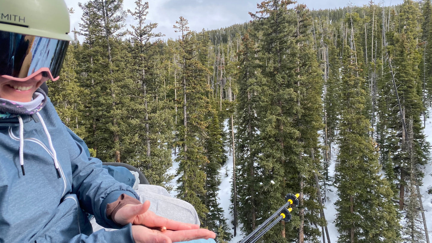 Photo of a woman on a ski lift using her Copper Rescue wand to clean her hands 
