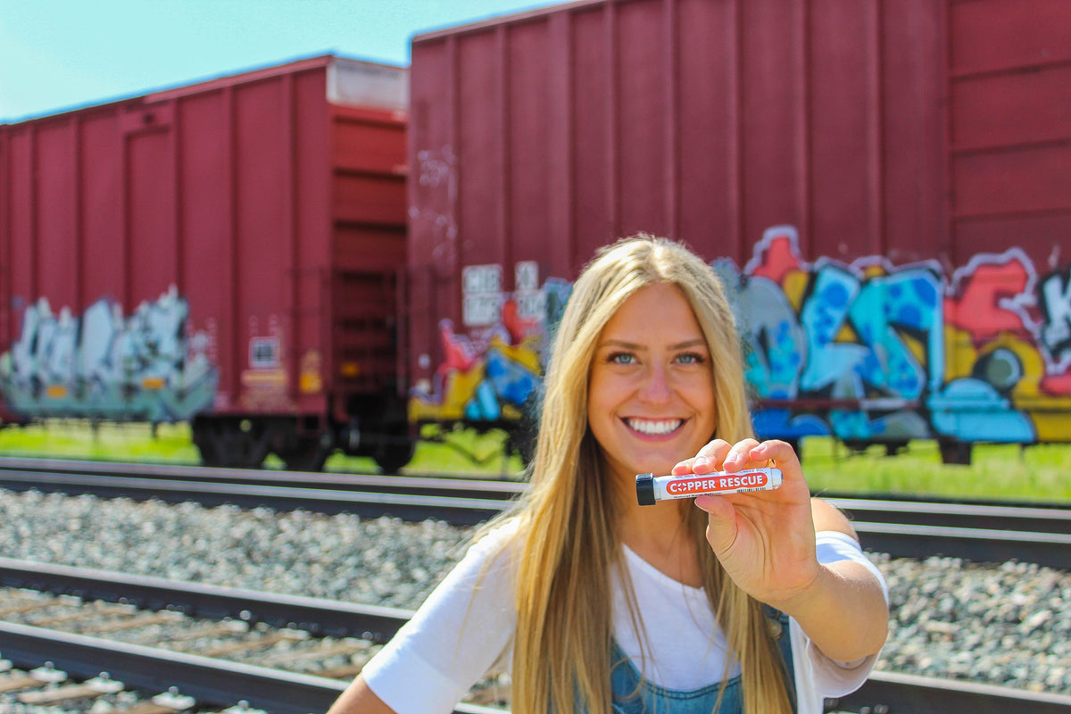 Photo of a smiling blonde woman holding the Copper Rescue germ fighting wand. 
